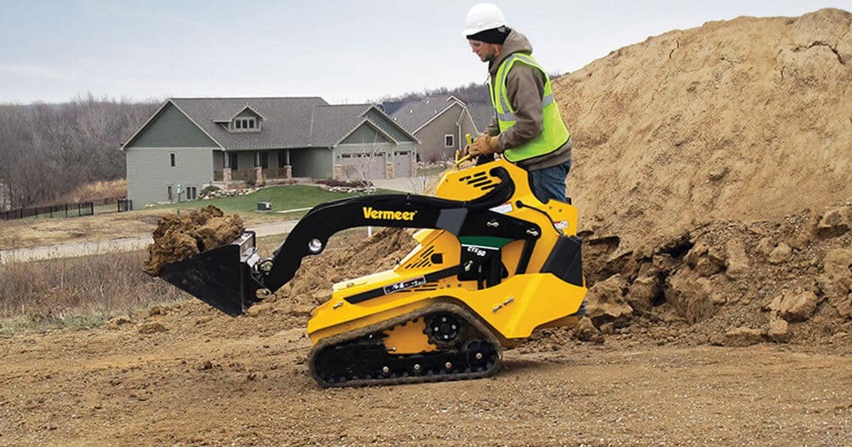 Photograph of worker using mini skid loader