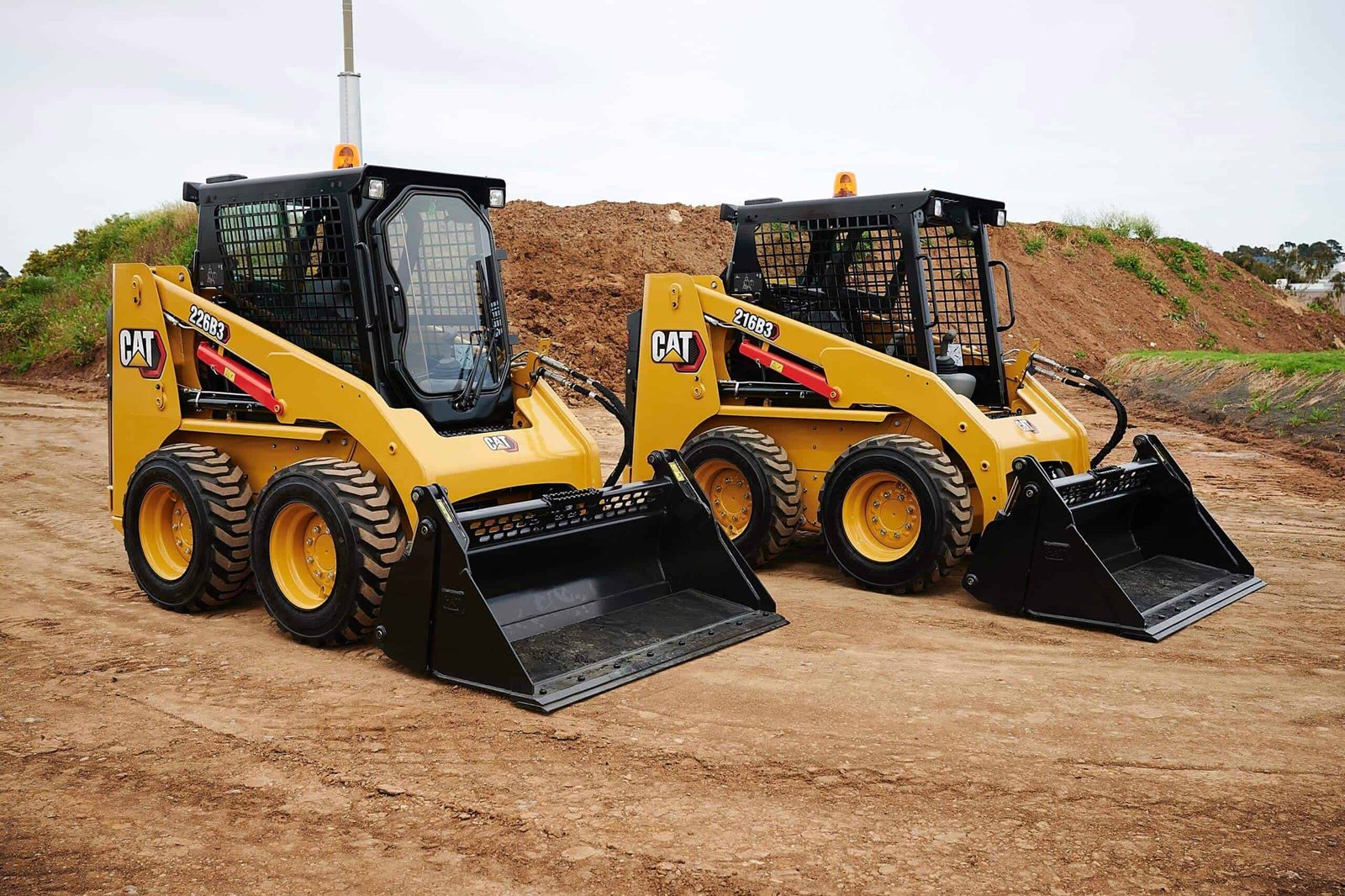 Photograph is showing two skid steer loaders working on site
